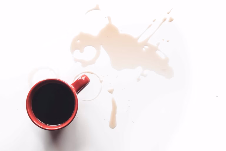 Red coffee cup tipped over with spilled coffee, symbolizing unexpected chaos and a mindset reset moment